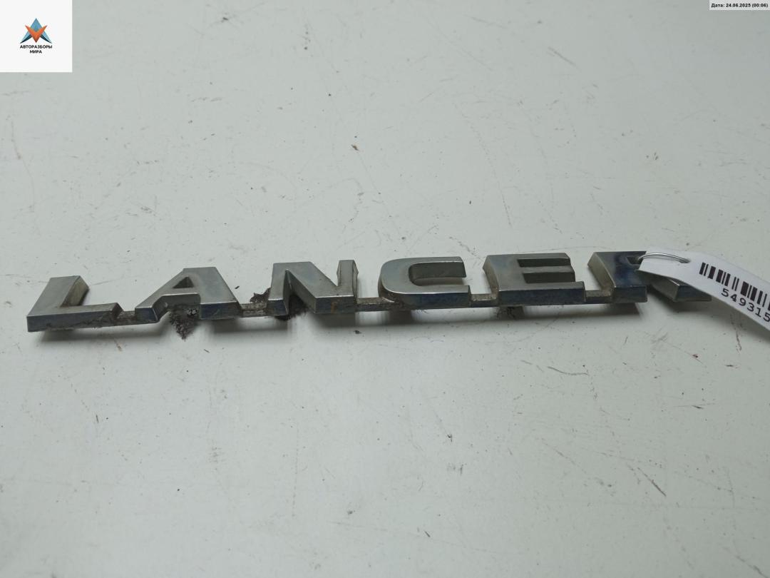 эмблема Mitsubishi Lancer 9 поколение 2003, 1.6 л., бензин, АКПП, серый, универсал, MN154915 - фото №1